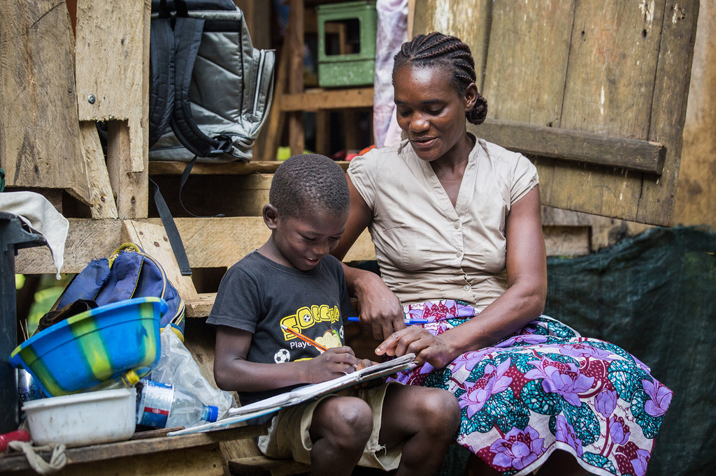 A mother helps her son with his homework at home in São Tomé and Príncipe.